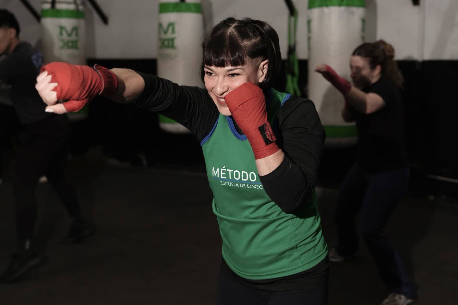 Mujer entrenando boxeo en clase grupal junto a sus compañeras